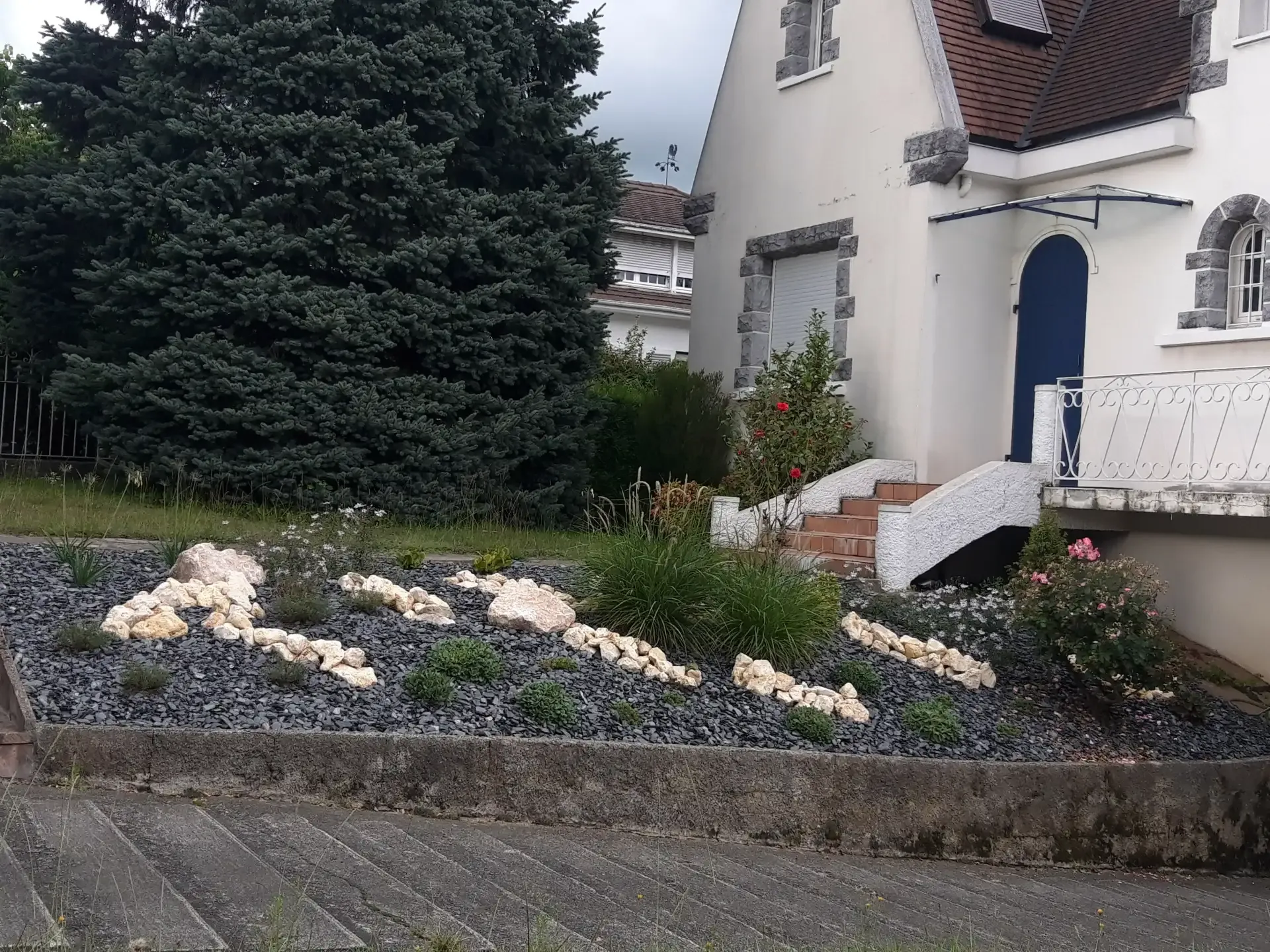 Jardin minéral devant une maison, avec ardoise, pierres claires et plantations