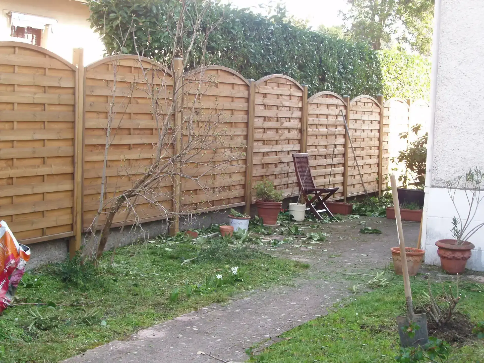Clôture en bois à panneaux arrondis bordant un chemin de jardin