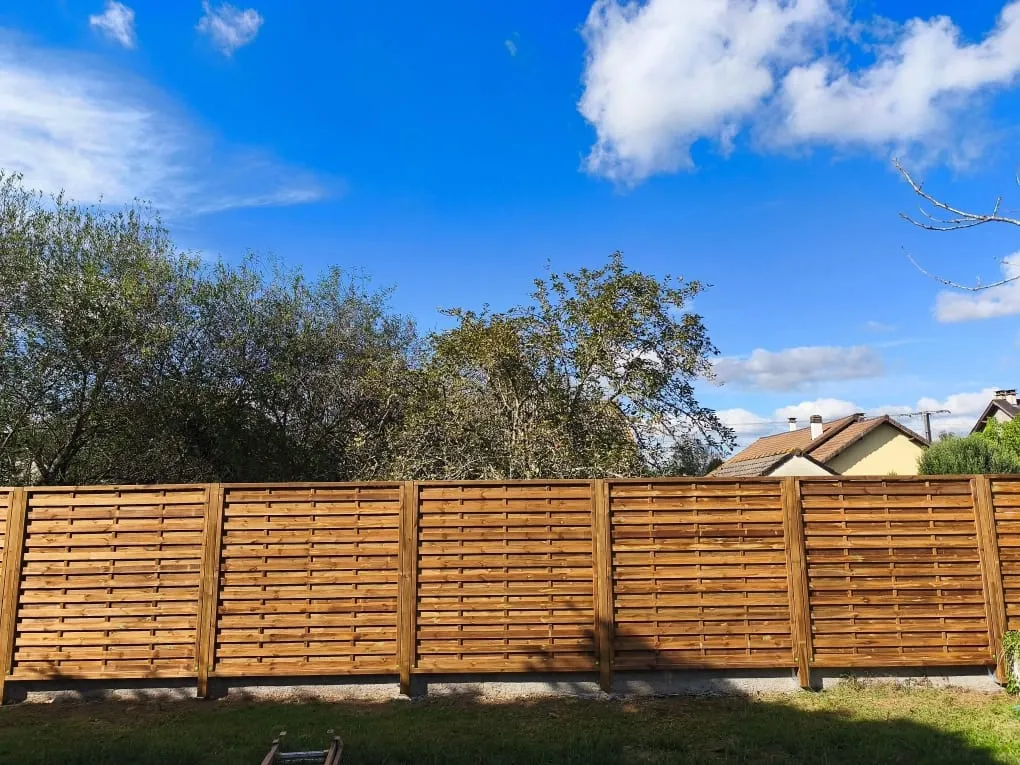 Clôture de jardin en panneaux de bois installée devant une maison