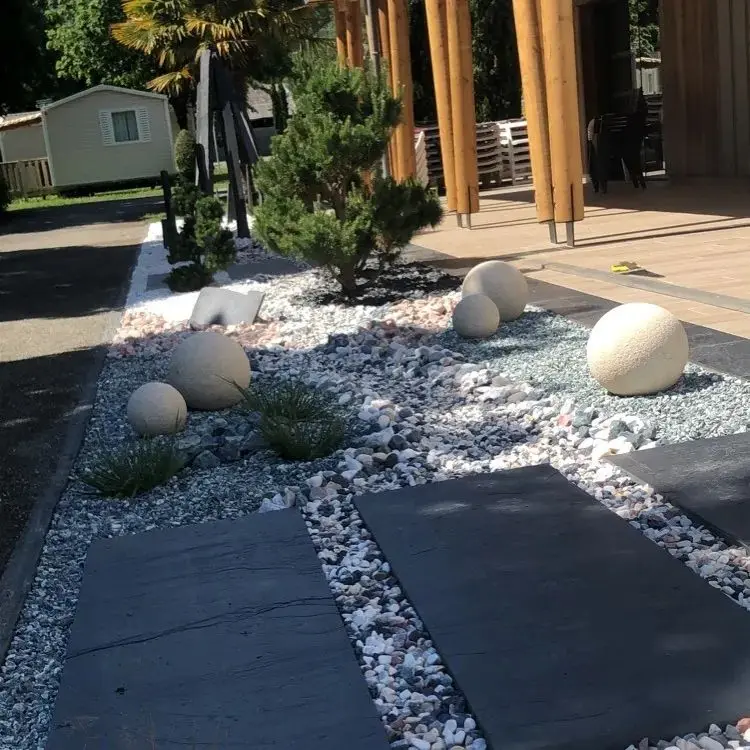 Jardin minéral avec dalles sombres, galets clairs et arbustes taillés