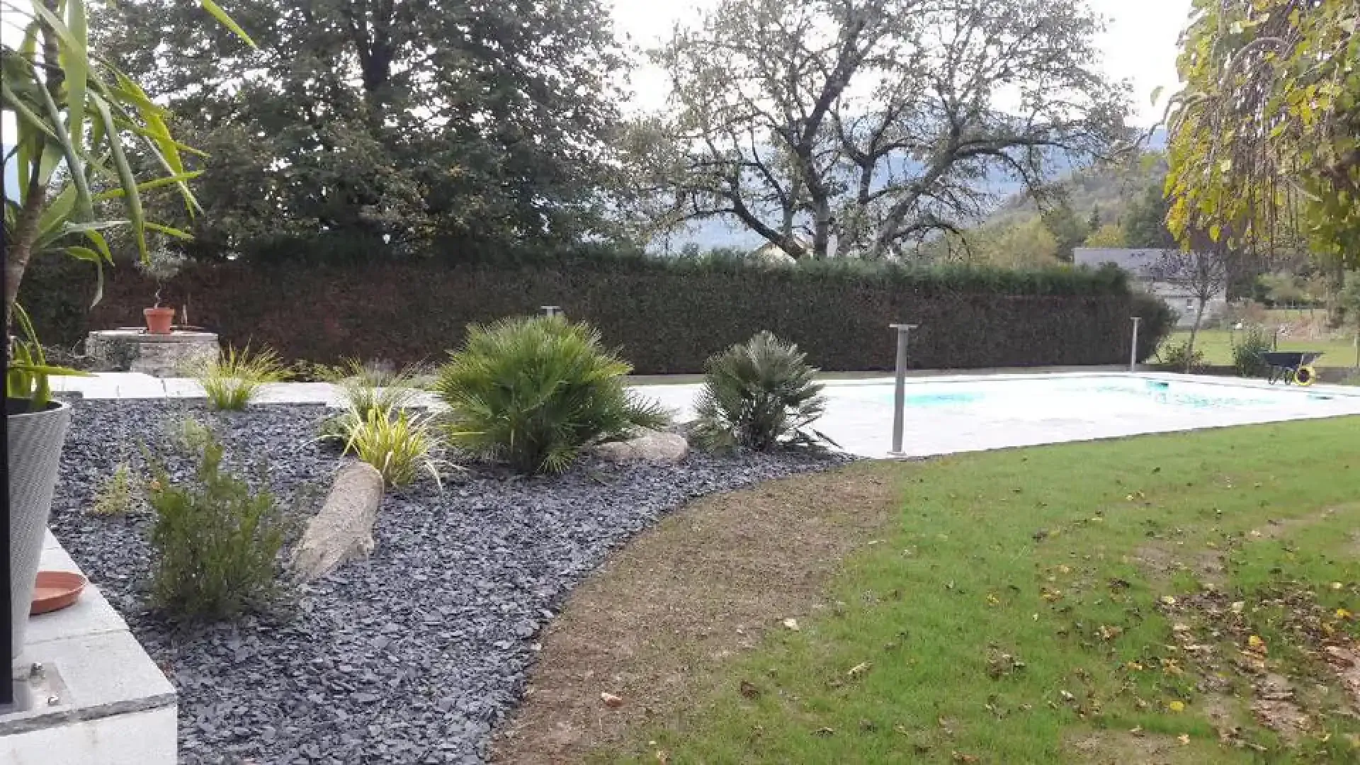 Massif d’ardoise et de végétaux près d’une piscine et d’une pelouse