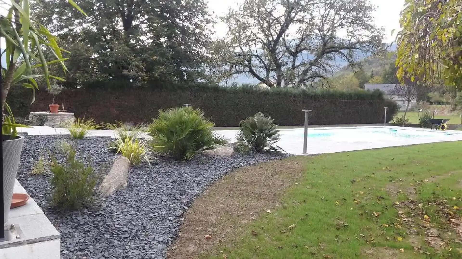 Massif d’ardoise et de végétaux près d’une piscine et d’une pelouse